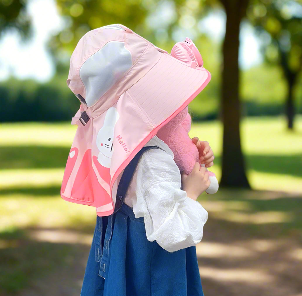 Child wearing a pink sun hat with cartoon character design, standing outdoors.